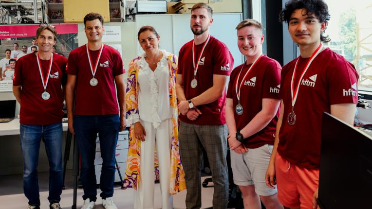 Gruppen Foto von Team Solidus zusammen mit Frau in einem farbigen Kleid