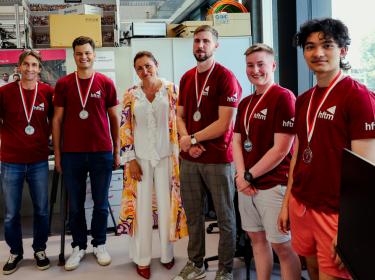 Gruppen Foto von Team Solidus zusammen mit Frau in einem farbigen Kleid