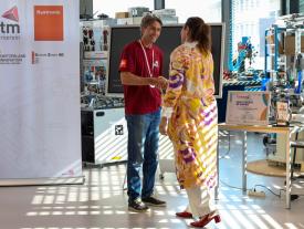 : Händeschütteln zwischen Mann im hftm T-Shirt und Frau bei Team Solidus Veranstaltung