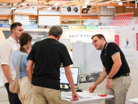 Besucher und Aussteller im Gespräch an einem Diplomarbeitsstand der hftm im Velodrom
